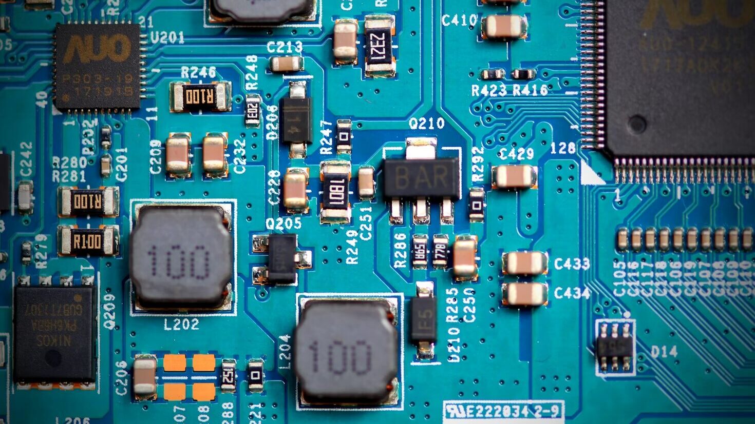 청록색 회로 기판(PCB) 위에 실장된 AUO 로고 IC 칩, 인덕터, 저항, 콘덴서 등 표면 실장 부품(SMD)의 근접 촬영 사진